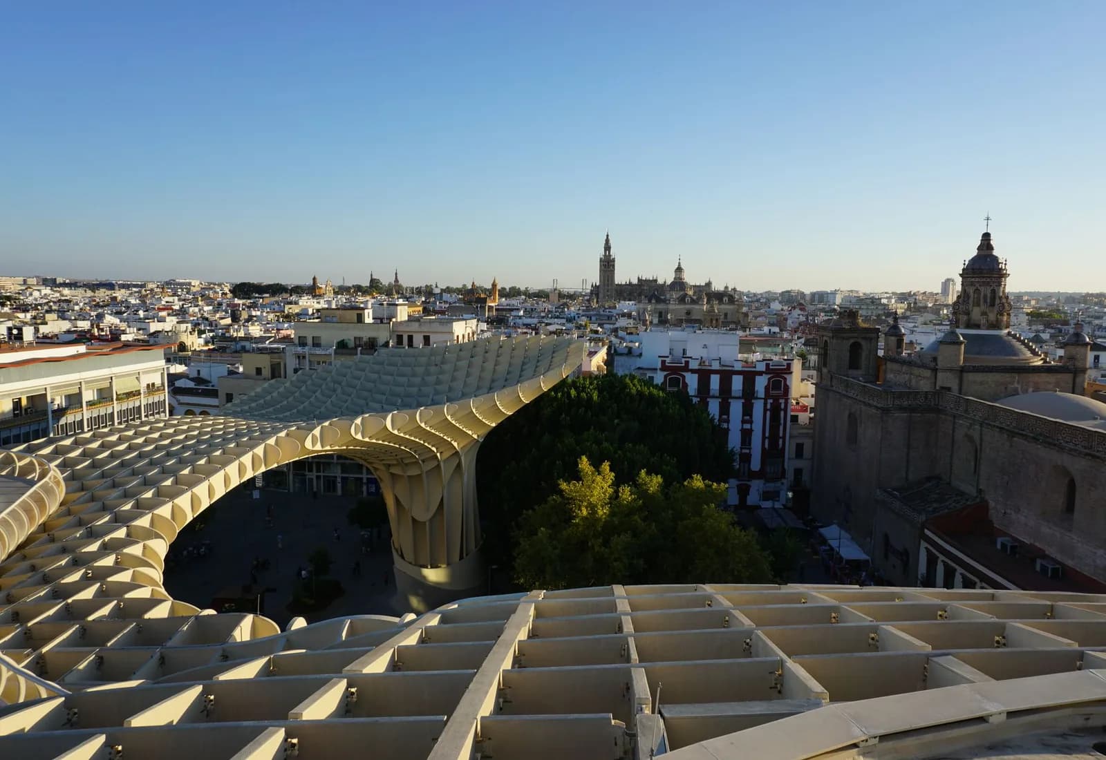 Panoramic view of Metropol Parasol and Seville skyline at sunset with historical landmarks.